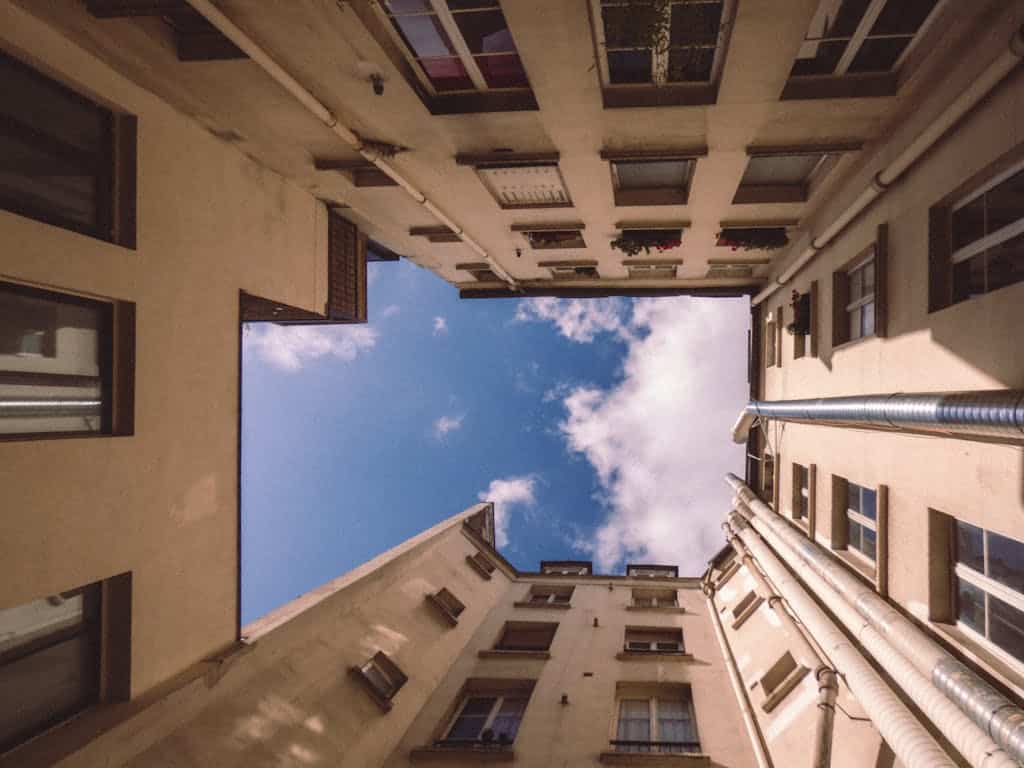 A captivating upward shot of a Parisian courtyard with classic architecture against a blue sky.